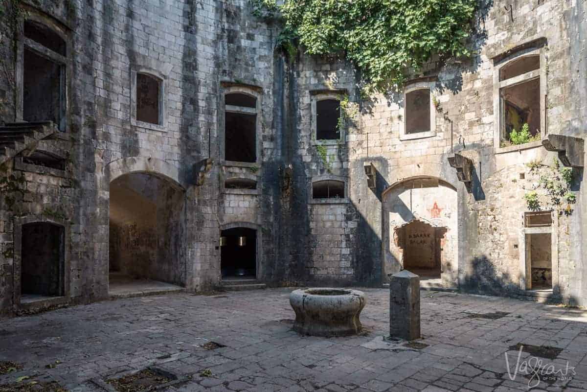 The centra courtyard of the ruins of the prison on Mamula Island overgrown with ivy. 