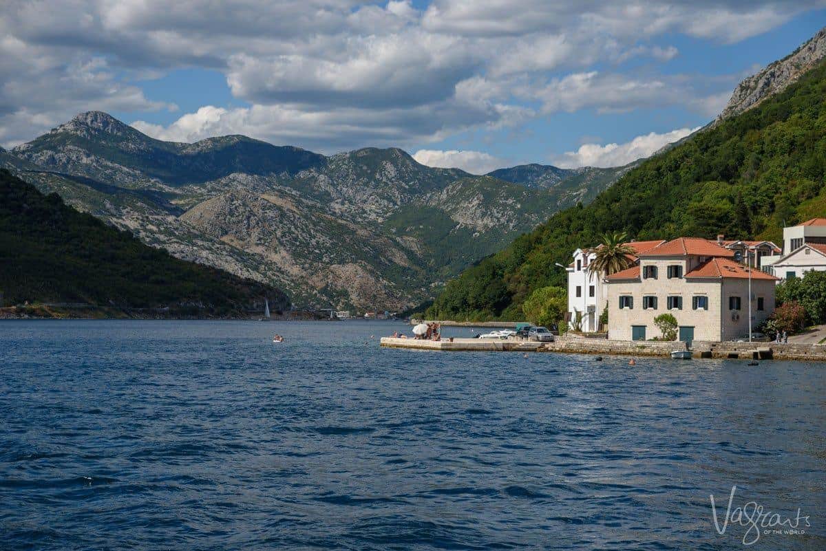 Mountains surrounding the blue water in Kotor Bay with houses on the waterfront in Montenegro.