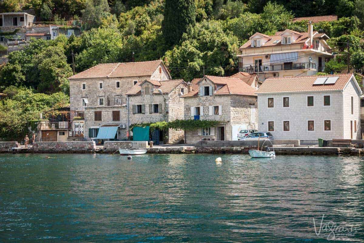 Boats moored at the front of typical stone houses in Boka Bay Montenegro. 