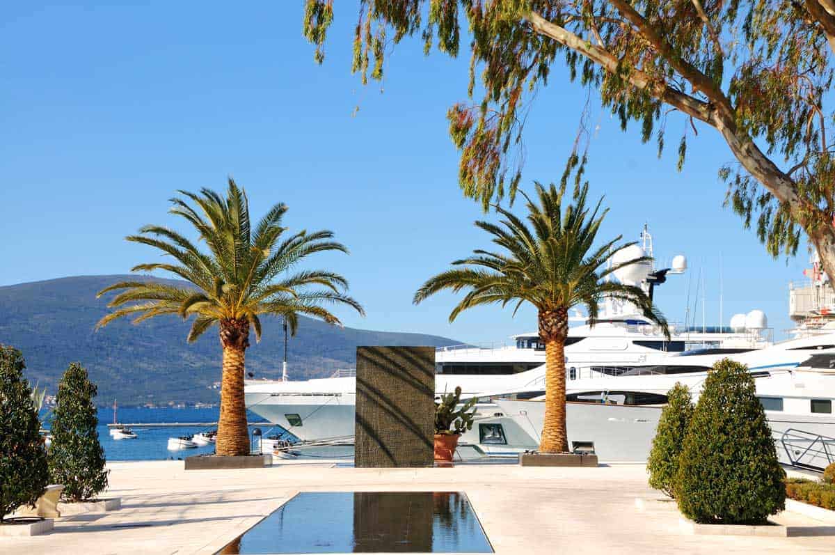 A super yacht parked in front of an infinity pool with palm tees in Tivat Montenegro. 